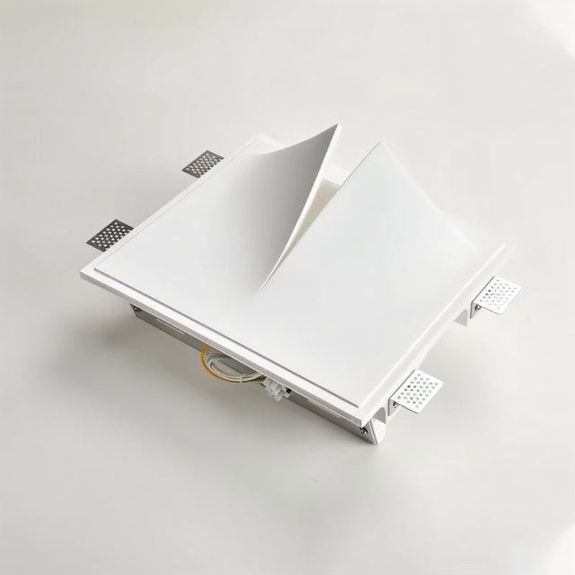 "A white square trimless wall light with a geometric design, showing its construction and mounting hardware, on a light surface."