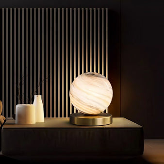 "Modern table lamp with marble glass globe shade and brass base, illuminating a contemporary living room."