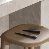 "Two sleek, tapered zinc alloy pull bars with a geometric profile in a dark finish, placed on a wooden surface in a modern setting."