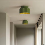 "Two green ceiling lights with ribbed shades and gold interiors, shown installed on a white ceiling in a hallway with a curtained window."