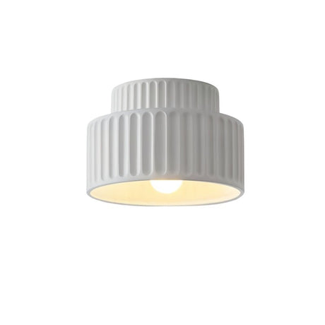 "A white ceiling light with a ribbed, cylindrical shade, shown lit up against a white background."
