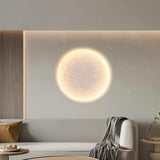 "A round, recessed wall light casting a warm, lunar-like glow on a light-colored wall."