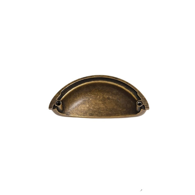 "A vintage brass cup-shaped drawer pull with a smooth, rounded design and a subtle black undertone, made of durable metal."