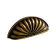 "A vintage brass fan-shaped drawer pull with detailed ridges and a black undertone, featuring a semi-circle shape and intricate dot accents."