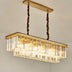 Modern rectangular chandelier with brass frame and clear crystal prisms, suspended from twisted bronze chains against a white ceiling.