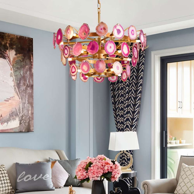 "Gold metal Zylan chandelier with layered circular design and pink agate slices hanging in a living room with a 'love' pillow."