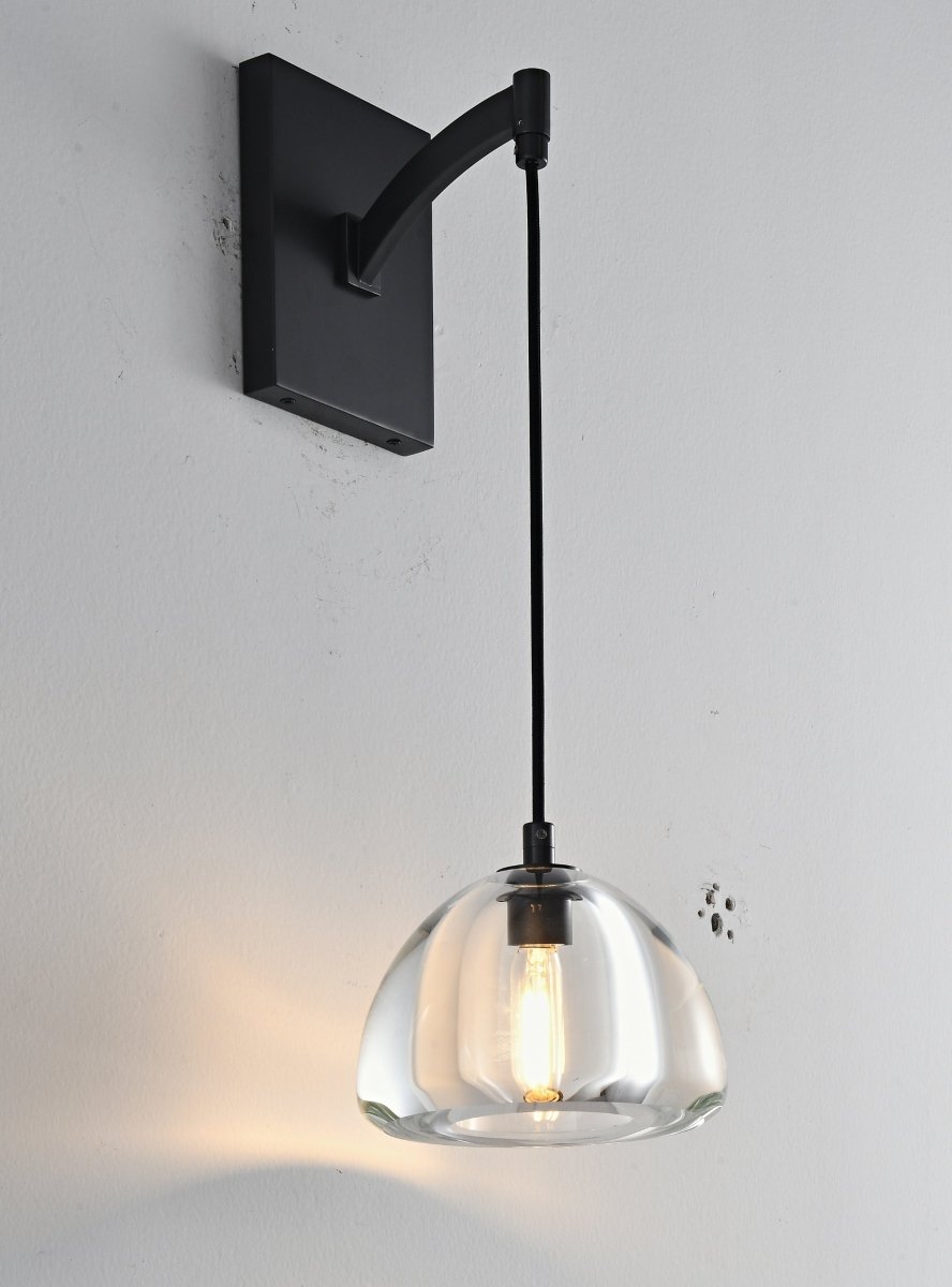 "A modern black wall lamp with a clear glass shade, blending elegance and minimalist design with a curved arm and rectangular base."