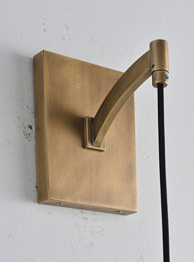 "Close-up detail of a modern brass wall lamp base and curved arm, showcasing its minimalist design."