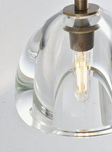 "Close-up detail of a modern wall lamp with a clear glass shade, showing the bulb and the design of the fixture."