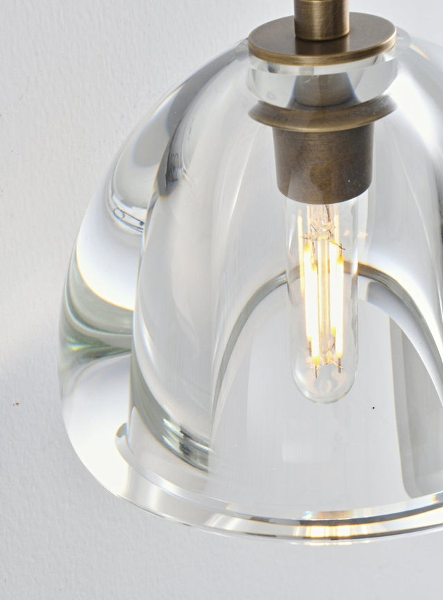 "Close-up detail of a modern wall lamp with a clear glass shade, showing the bulb and the design of the fixture."