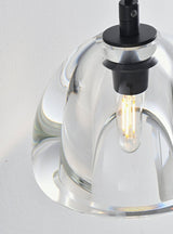 "Close-up detail of a modern glass wall lamp with a clear shade, showing the bulb and intricate design."