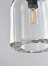 "Close-up detail of a modern glass wall lamp with a clear shade, showing the bulb and intricate design."
