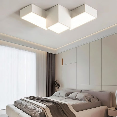 "A white geometric ceiling light with interlocking rectangular forms, illuminating a modern bedroom with diffused light."