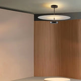 "A minimalist ceiling light with a circular acrylic diffuser and a sleek metal frame in a modern living room setting."