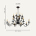 Black wrought iron chandelier with twelve candle-style lights against a light beige background.