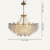 Glass chandelier with brass accents and draped textured glass panels on cream background.