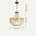 Gold brass chandelier with layered textured glass shades suspended from chain against cream background.