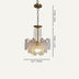 Brass and frosted glass pendant chandelier with decorative filigree design hanging from chain against neutral background.