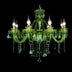 Green crystal chandelier with eight illuminated candle-style arms and hanging glass prisms on black background.