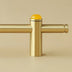 Brass pull bar with yellow spherical finial on beige background.