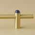 Brass pull bar with blue lapis lazuli sphere finial mounted on beige wall.