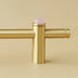 Brass pull bar with pink quartz sphere finial against a beige wall.