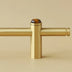 Brass pull bar with tiger eye stone finial on neutral beige background.