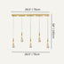 Gold linear chandelier with five hanging teardrop pendant lights suspended from a wooden rail against a light background.