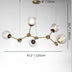 Brass chandelier with five frosted glass globe shades suspended from a central canopy against a white wall.
