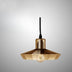 Gold brass pendant light with geometric shade and exposed filament bulb on gray background.