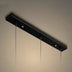 Black rectangular pendant light fixture with multiple hanging cords against a cream ceiling.