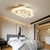 Cloud-shaped LED ceiling light with gold stars in warm white finish, mounted in modern bedroom above bed.