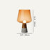 Modern table lamp with amber glass shade and gray concrete base, displayed against neutral background.