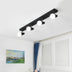 Black track ceiling light with four white globe shades mounted above windows in a bright modern bedroom.