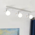 Three-light ceiling fixture with white globe shades and brushed metal accents mounted on a white ceiling.