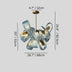 Modern chandelier with textured blue and white ribbons, brass accents, and warm interior lighting on gray background.