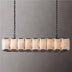 Linear chandelier with dark bronze frame and segmented alabaster shades, suspended by chains against gray background.