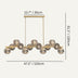 Brass linear chandelier with ribbed glass shades suspended from decorative rosettes, against a light background.