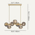 Brass linear chandelier with five ribbed glass orbs and ornate brass canopies on cream background.