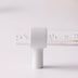 White cylindrical handle mounted on clear acrylic rod with water droplets against light pink background.