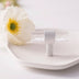 Clear acrylic cabinet knob and pull bar in brushed nickel finish displayed on white surface with daisy flower.