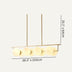 Linear chandelier with brass finish and frosted glass globes, suspended against a beige background.
