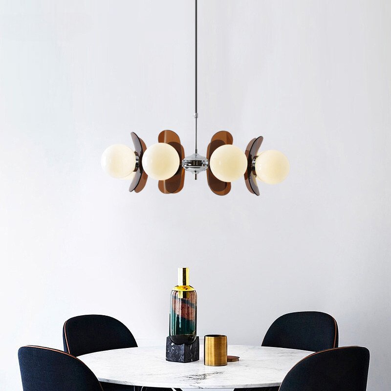 Mid-century modern chandelier with walnut wood accents and frosted glass globes hanging above a marble dining table.